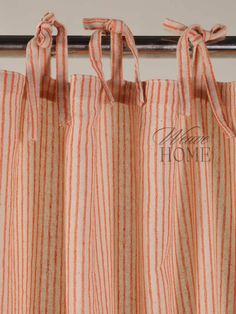 an orange and white striped curtain hanging from a metal rod with two ties on it