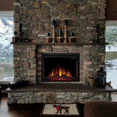 a living room with a stone fireplace and large windows