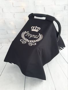 a black bag with a crown on it sitting next to a white brick wall in the background