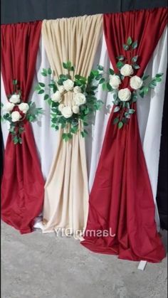 three red and beige drapes with white flowers on them, along with greenery