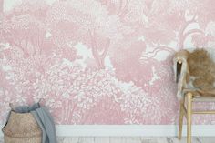 a chair sitting in front of a pink wallpapered with trees and flowers on it