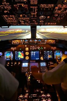 two pilots are in the cockpit of an airplane at night, with multiple screens showing flight information