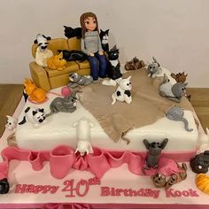 a woman sitting on top of a birthday cake with cats and dogs around the cake