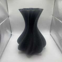 a black vase sitting on top of a white table