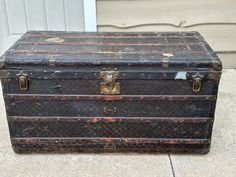 an old trunk is sitting outside on the concrete near a door with a white door in the background