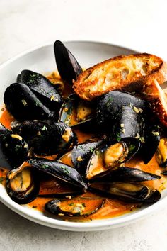 a white bowl filled with mussels and bread