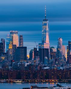 the city skyline is lit up at night, with skyscrapers in the foreground