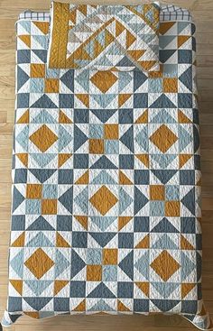 an orange and blue quilt on top of a wooden floor