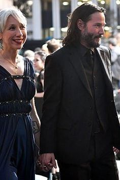 a man and woman walking down the street in front of a large group of people