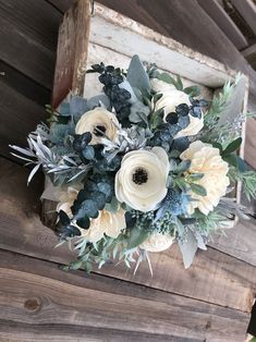 a bouquet of flowers hanging from the side of a wooden structure with greenery and foliage