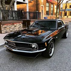 an old muscle car parked on the side of the road in front of a building