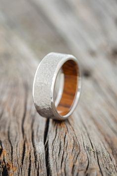 a wooden ring sitting on top of a piece of wood with silver inlays