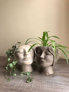 two clay heads with plants growing out of them