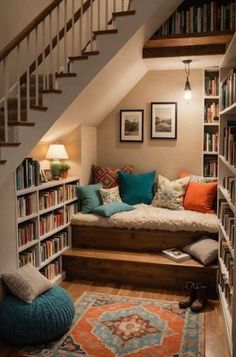 a living room filled with lots of books and furniture next to a stair case full of books