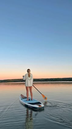 a woman standing on top of a paddle board in the water with a oar