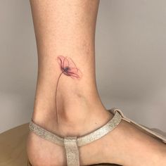 a woman's foot with a flower tattoo on the side of her leg,