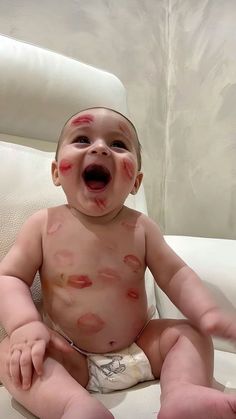 a baby with blood all over it's face sitting on a chair