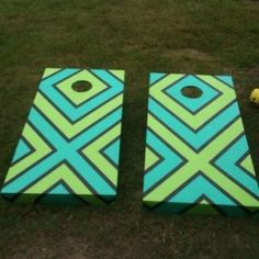 two blue and green cornhole boards sitting on top of the grass next to a yellow ball