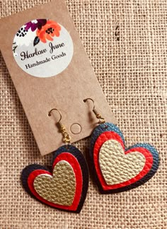 two red, white and blue heart shaped earrings on top of a piece of cardboard