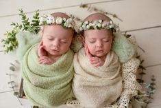 two newborn babies wrapped in blankets with flowers on their heads