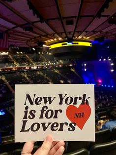 someone holding up a sign that says new york is for lovers in front of an audience