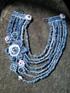 a blue necklace with flowers on it sitting on top of a rock