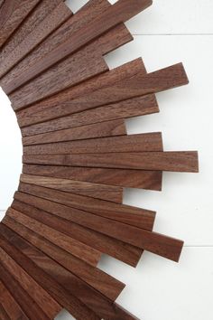 a circular mirror made out of wooden planks on a white wall with a reflection in it