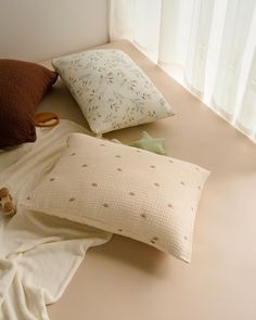 three pillows are laying on the floor next to each other in front of a window