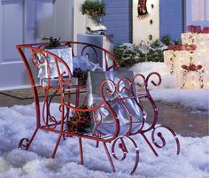 a sleigh with presents on it sitting in the snow next to a house