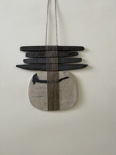 a clock made out of black and white stones hanging on a wall next to a string