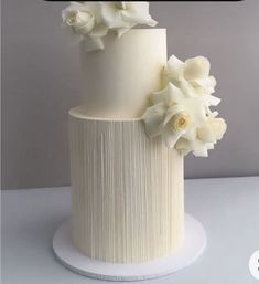 a three tiered cake with white flowers on top and the words wedding cakes written below it