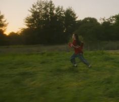 a person running in the grass with a frisbee