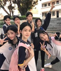 group of young women posing for the camera with their hands in the air and holding up peace signs