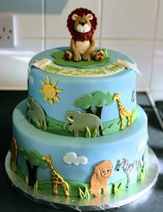 a three tiered cake decorated with animals on it's sides and an animal topper