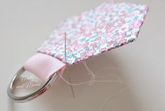 a close up of a pink and white flowered fabric with a metal hook attached to it