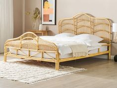 a bamboo bed frame with white sheets and pillows in a neutral colored bedroom, next to a painting on the wall