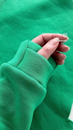 a person's hand on top of a green shirt that is folded in half