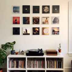 a record player sitting on top of a white shelf next to a book case filled with books