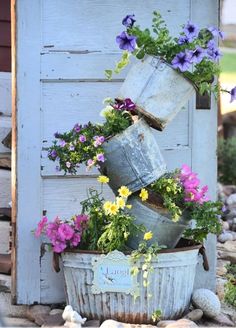 some flowers are growing in buckets on the side of a building with a blue door