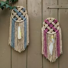 two woven wall hangings on the side of a wooden fence with plants in them