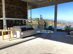 a living room filled with furniture next to a large glass wall covered window overlooking the city