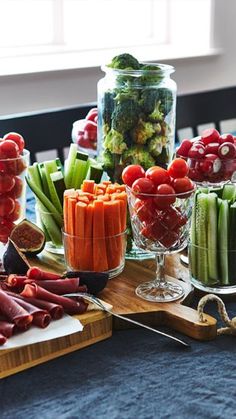 a table topped with lots of different types of vegetables and meats on top of wooden cutting boards