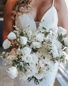 a bride holding a bouquet of white flowers