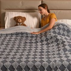 a woman laying in bed under a blanket with a teddy bear on the pillow next to her