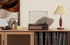 a record player sitting on top of a wooden cabinet next to a lamp and mirror