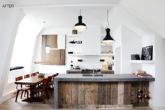 a kitchen with an island made out of wooden planks and lights hanging from the ceiling