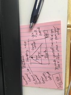 a piece of pink paper with writing on it next to a pen and clipboard