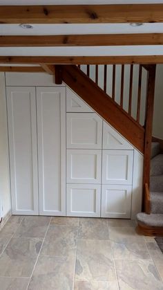 an empty room with stairs leading up to the second floor and storage space below it