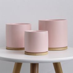 three pink pots sitting on top of a white table