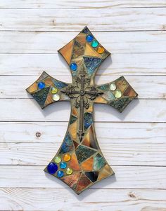 a cross made out of stained glass sitting on top of a wooden wall